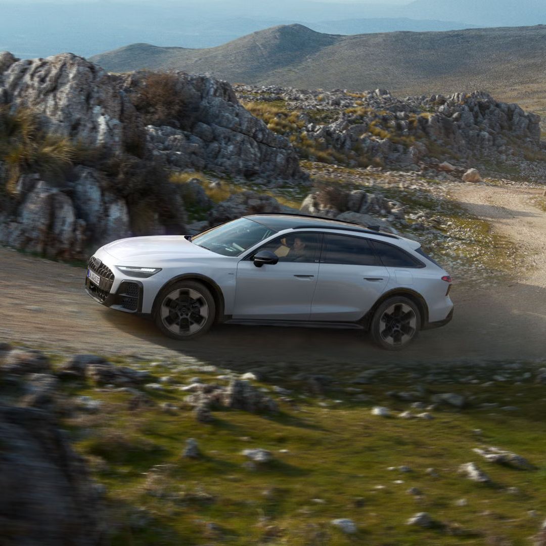 Der Audi A6 allroad e-hybrid durchquert eine steile Schotterstraße in felsiger Umgebung.