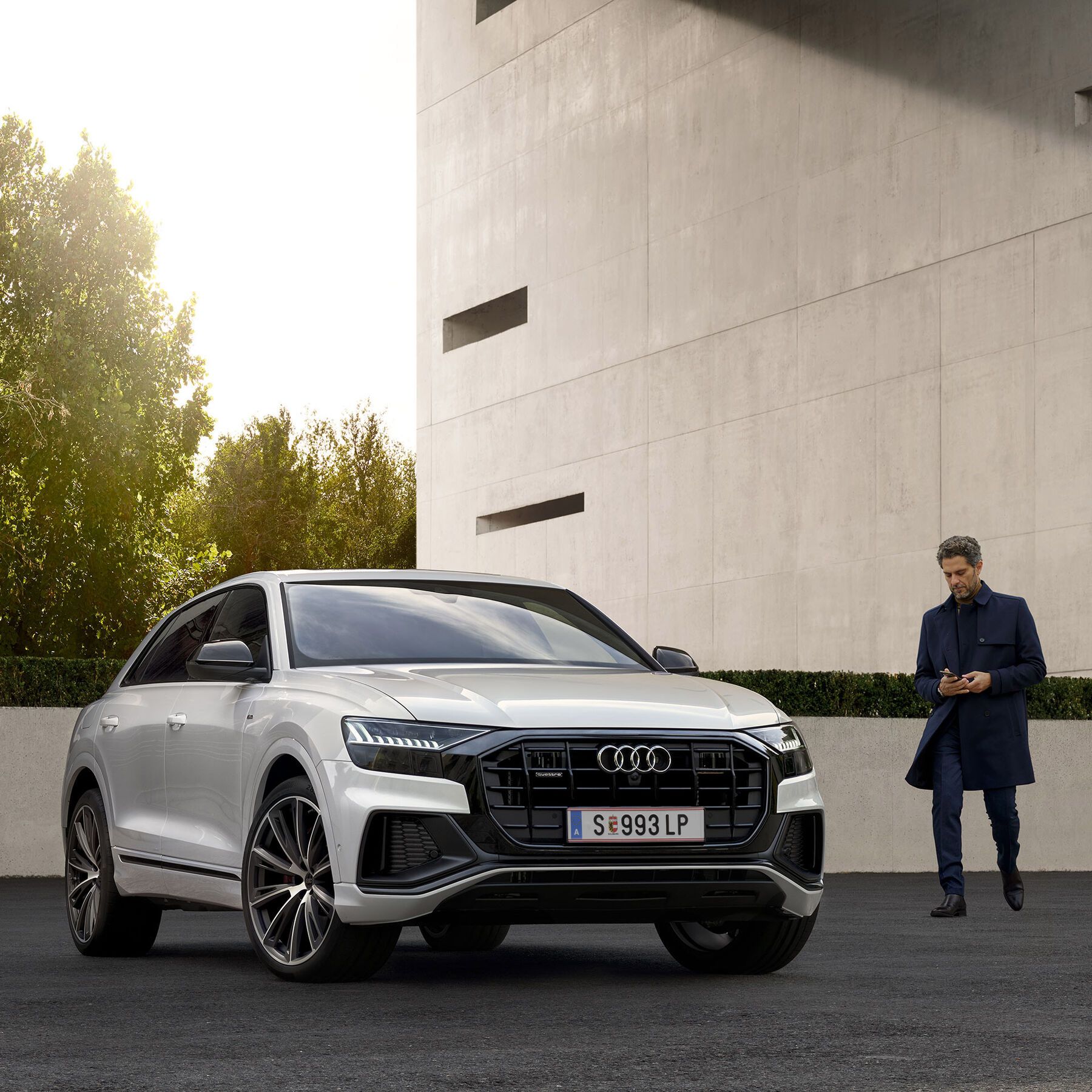 Audi Q5 55 TFSI e quattro in Blau beim Laden vor einem Haus