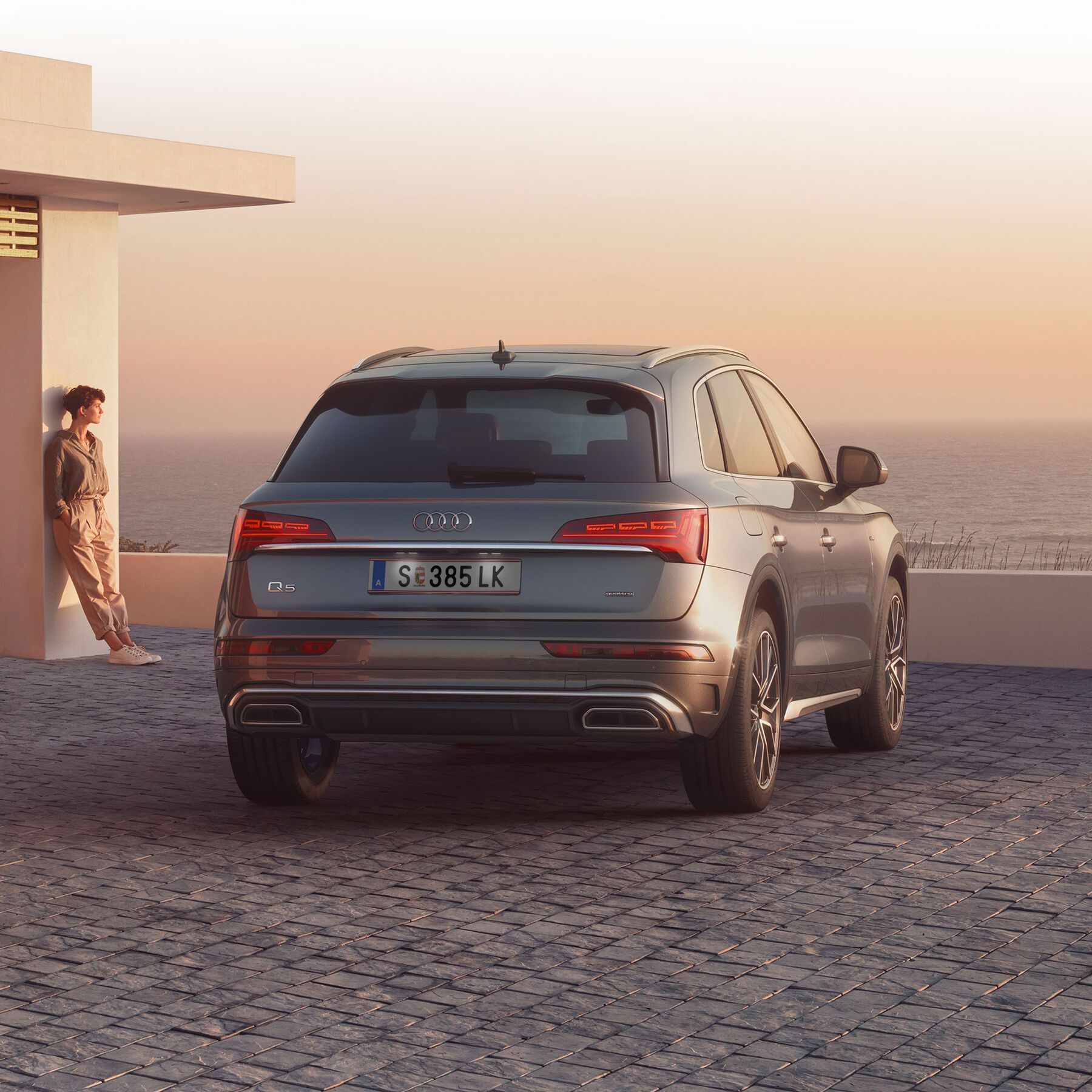 Audi Q5 55 TFSI e quattro in Blau beim Laden vor einem Haus