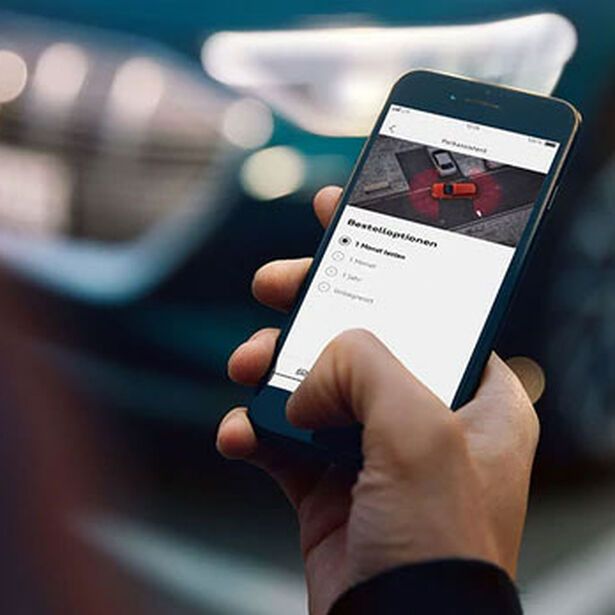 Mann steuert mit seinem Smartphone seinen Audi