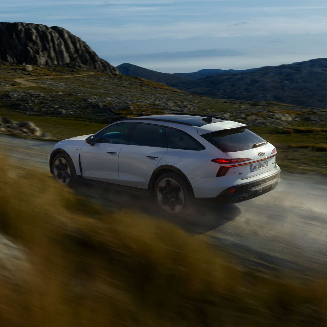 Der Audi A6 allroad e-hybrid von der Seite in voller Fahrt auf einer Gebirgsstraße.