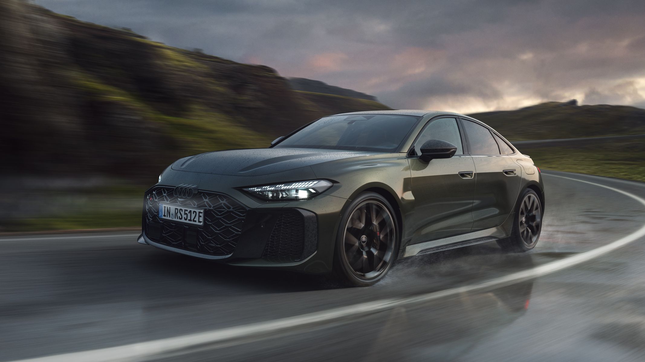 Die RS 5 Limousine schräg von vorn fährt eine Kurve auf einer Gebirgsstraße.