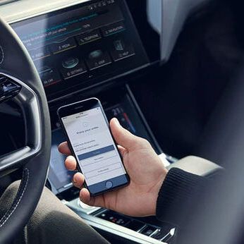 Ein Audi Lenkrad und eine Männerhand die ein Handy hält