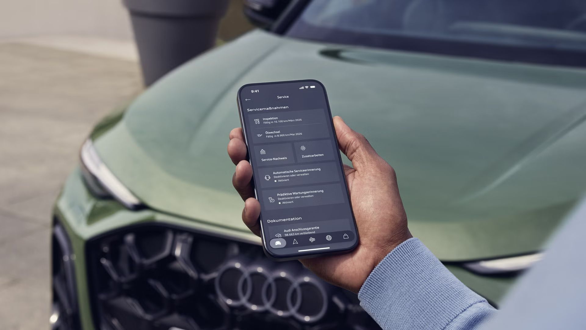 Смарттелефон в мъжка ръка до Audi Q5 с отворен дисплей на управление на сервизните услуги