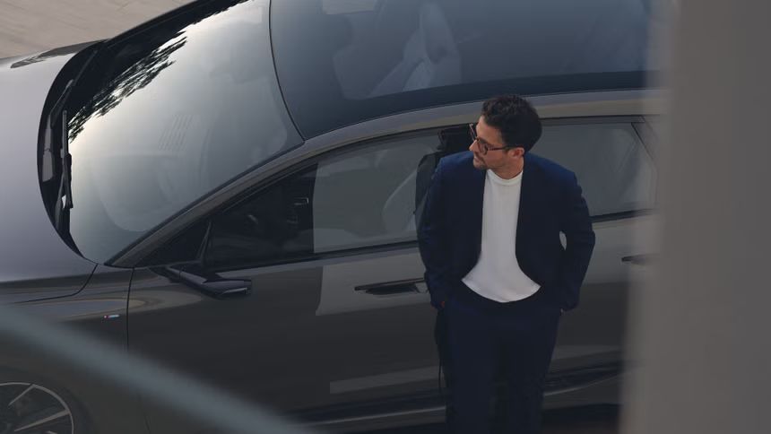 Мъж с очила се е облегнал на Audi автомобил