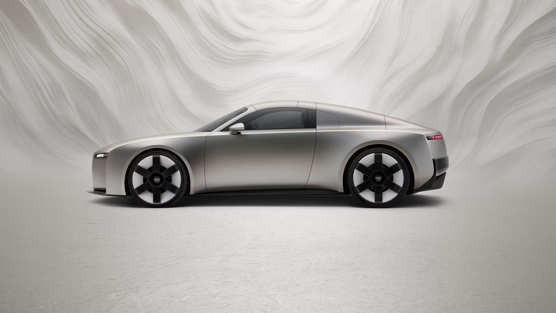 Seitliche Ansicht eines Audi Concept C vor einem graphischen Hintergrund