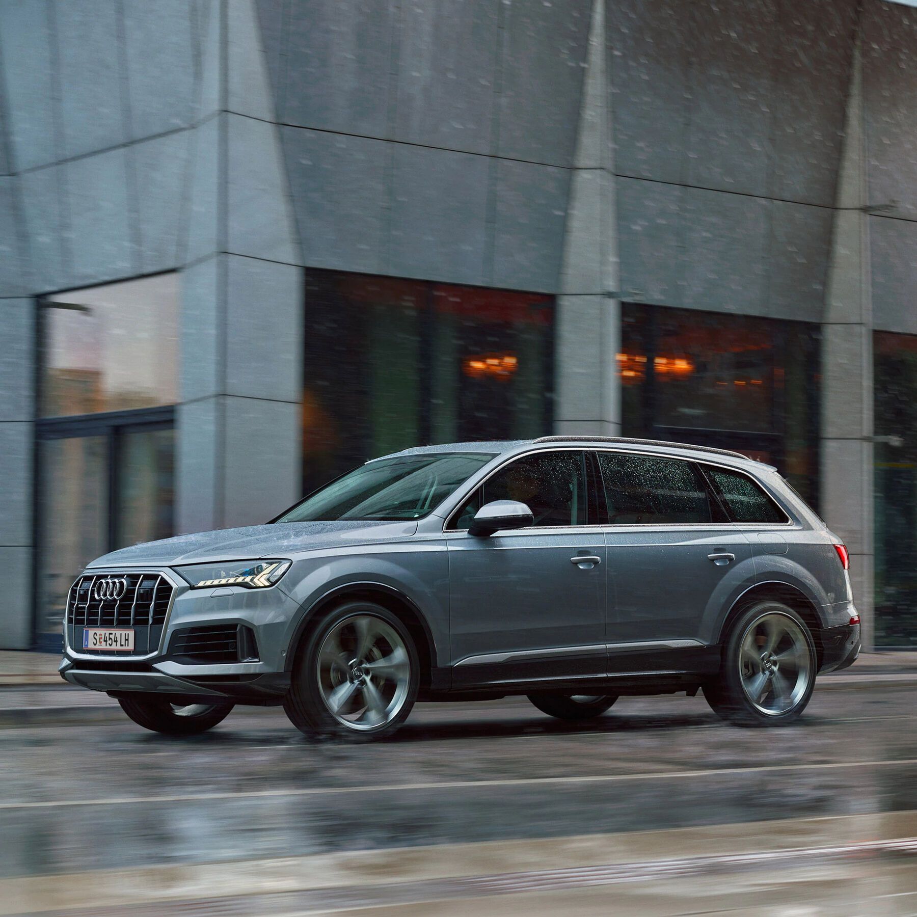 Audi Q5 55 TFSI e quattro in Blau beim Laden vor einem Haus