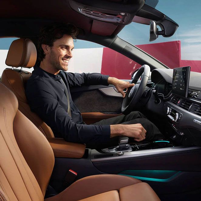 Ein Mann lächelt und fährt in einem Audi
