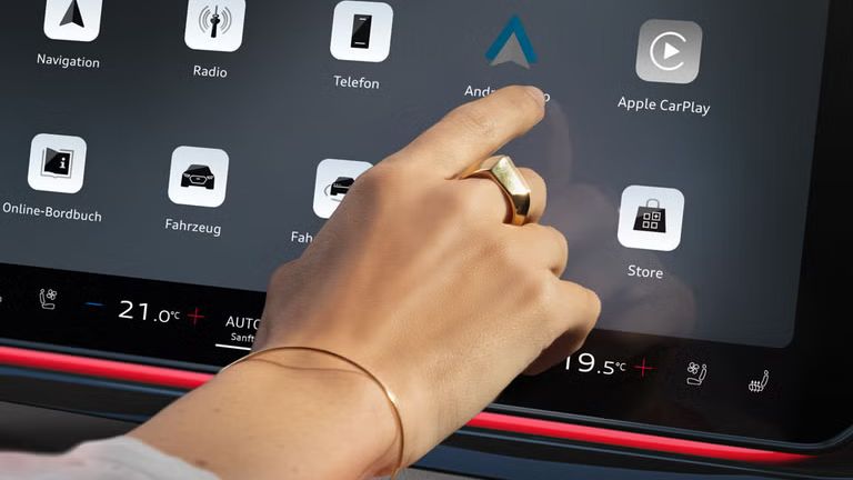 MMI система в близък план с насочен пръст към иконата на Android Auto